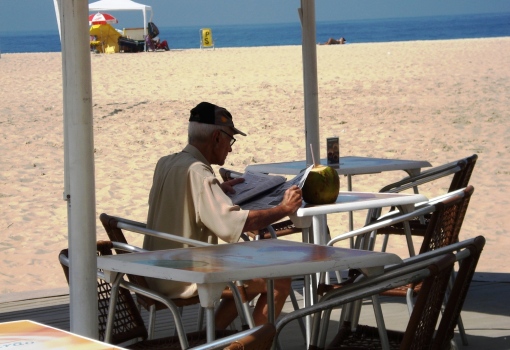 Brasileiro lendo com café da mnhã, praia 1603